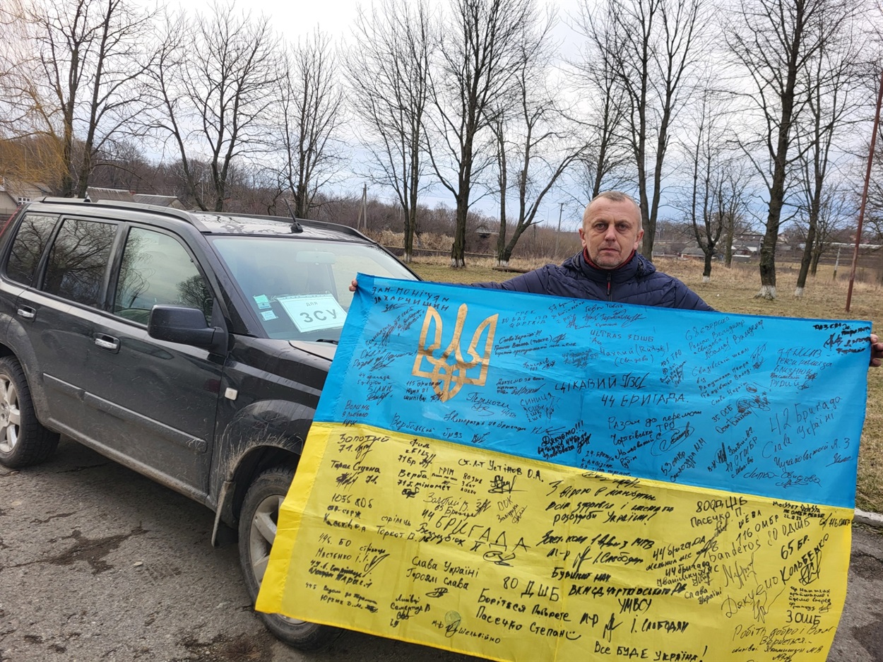 Волонтер зі Свидови Руслан Глова з прапором, підписаним за майже два роки волонтерської діяльності бійцями з передової